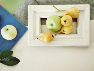 Fresh pears and apples in a wooden frame, top view, concept of healthy nutrition, harvest, season of summer, autumn
