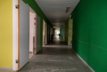 A long corridor with full of open doors and a window in the end