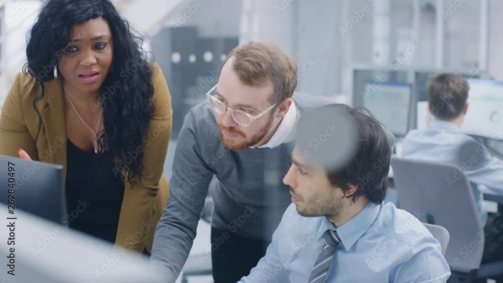 Poster in bright modern office: young businessman sitting and working at his desktop computer with project 