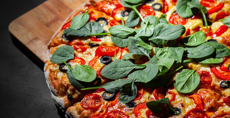 Pizza with Mozzarella cheese, Tomatoes, pepper, olive, Spices and Fresh spinach. Italian pizza. Pizza Margherita or Margarita on Dark grey black slate background