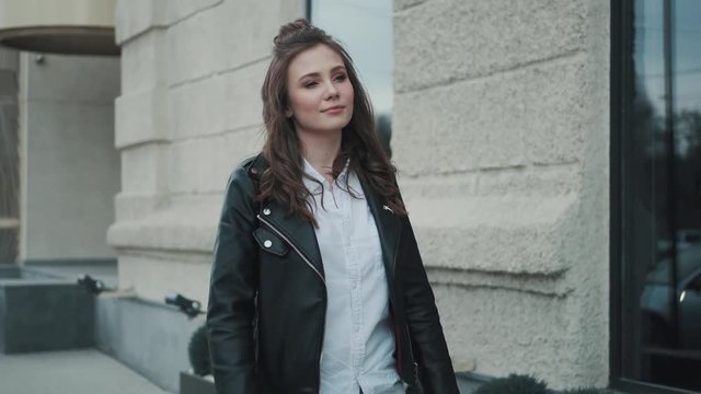 hipster girl walking in the city. portrait of a young woman in a leather jacket on the street.