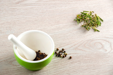 Green ceramic mortar and pestle with spilled mixture of pepper beans at the vintage background