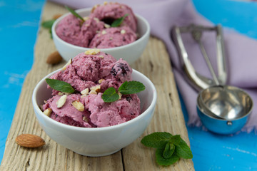 Ice cream with berries. Ice cream balls in a white bowl with nuts and mint.