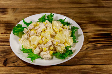 Festive salad with chicken breast, sweet corn, canned pineapple and mayonnaise on wooden table