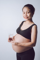Beautiful woman pregnant holding a glass of drinking water on a white background