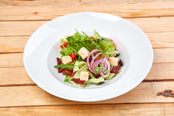 vegetarian salad with dried tomatoes and croutons on the wooden background