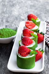 Matcha green tea crepe with whipped cream and strawberry on wooden table