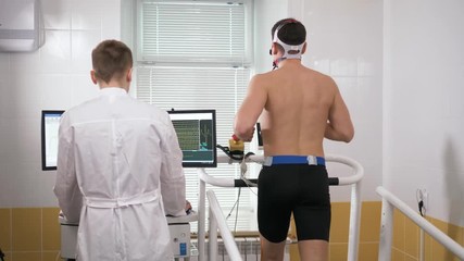Muscular athlete with mask running on treadmill in gym for monitoring his performance. Sportsman in sports science lab measuring his performance cardio respiratory test professional athlete - Powered by Adobe
