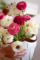 Romantic floral composition with a pink Ranunculus flowers closeup. Beautiful bouquet of flowers in white basket