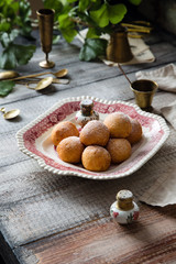 Fototapeta na wymiar Homemade small round ball donuts sprinkled with powdered sugar on vintage plate