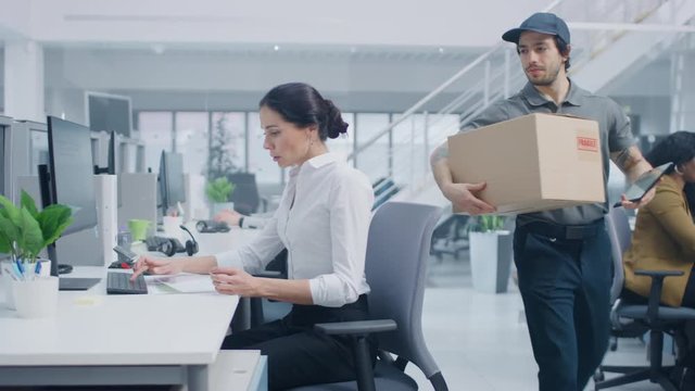 Happy Delivery Man Enters Corporate Office, Hands Package to a Beautiful Businesswoman, She signs Her Signature on the Tablet Computer. Big Bright Modern Business Company Office. Slow Motion