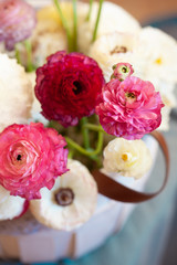 Romantic floral composition with a pink Ranunculus flowers closeup. Beautiful bouquet of flowers in white basket