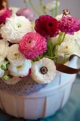 Romantic floral composition with a pink Ranunculus flowers closeup. Beautiful bouquet of flowers in white basket
