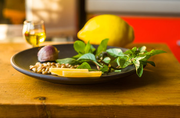 Fresh ingredients for preparing Italian pesto sauce - lemon basil sprigs, peeled seeds of cedar nuts, large garlic clove, Greek olive oil, Parmesan cheese