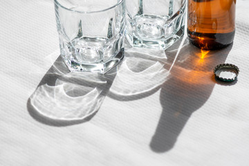 Two cristal glasses and one beer bottle on a white paper tablecloth.