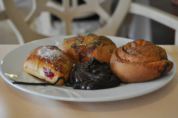 Three buns and chocolate on a white plate