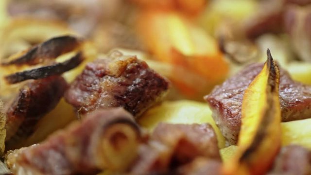 Closeup of delicious hot potatoes and meat cooked on grill charbroiled barbecue on brazzer on blurred smoky background