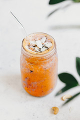 Orange and purple vegan smoothie is made from blueberry, sea buckthorn, coconut cream, nuts and chia on a white background. The concept of healthy summer food and drink.