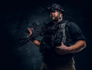 Bearded special forces soldier or private military contractor holding an assault rifle and observes...