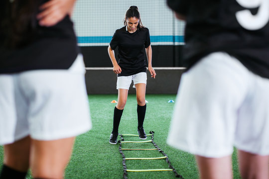 Female soccer player training in football field.