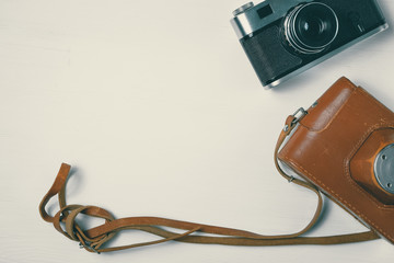 Vintage camera with leather case on a wooden white background.