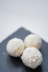 White coconut candy balls in plate shale dishes on rustic wooden background.