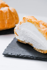 sweet buns in a cut with jam and cream on a shale dishes and wooden background.