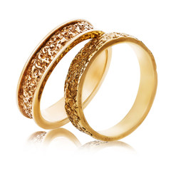Two gold wedding rings with an abstract surface isolated on a white background. The photo was taken...