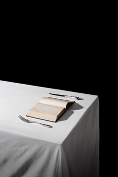 An Open book on the table, with a fork and knife