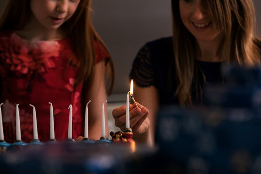 Hanukkah: Parent Helping Girl Light Shamash