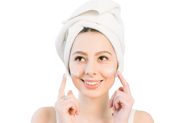 happy young girl with a towel on her head apply a cleansing mask on her face. Isolated on a white background