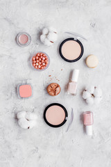 Make-up artist desk with powder, nail polish, decorative cosmetics and macaroon cookies on stone background top view