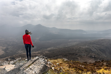 Fototapeta premium une femme de dos au sommet d'une montagne admire le paysage 