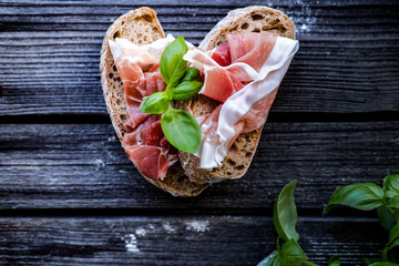 Small sandwiches with meat and basil on the black table.