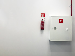 A fire extinguisher and a fire-hose on concrete wall