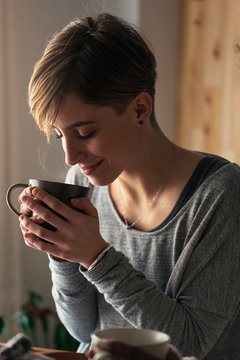 Young woman holding cup with hot drink