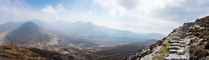 vue panoramique sur des montagnes avec un chemin de pierre sur la droite