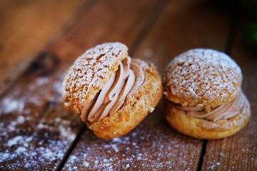 Delicious sandwich cakes with custard creme and powdered sugar on wooden table