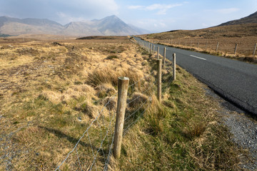Fototapeta na wymiar des barbelés au bord d'une route au milieu de grand espace naturels en Irlande