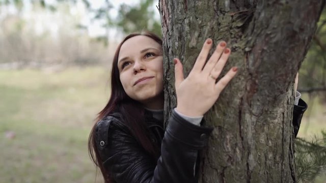 Young woman hugging tree in the forest. Smiling young woman nature lover relax on summer day hug a tree enjoy in beautiful day