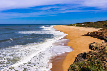 Foamy Atlantic ocean wave on deserted Nazare beach, Portugal.