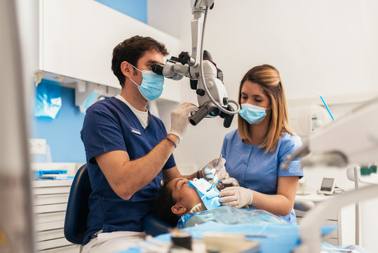 Dentists during a dental intervention using microscope.
