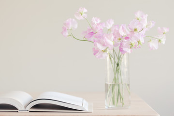 An open book and a vase of pink sweet pea flowers