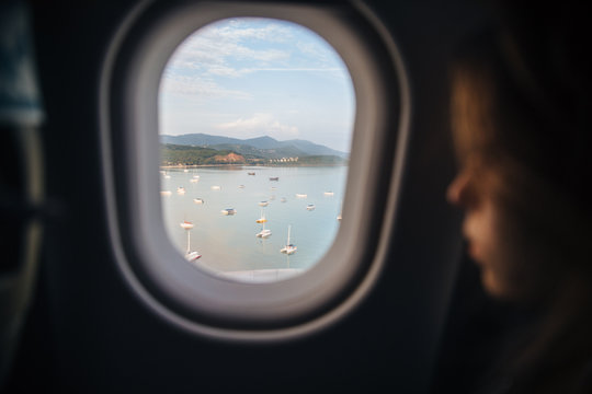 Profile of a young woman looking out of the window in the plane