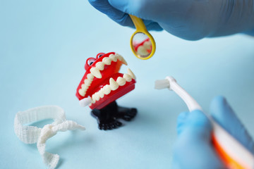Closeup of gloved dentist's hands visiting vampire wind up teeth toy