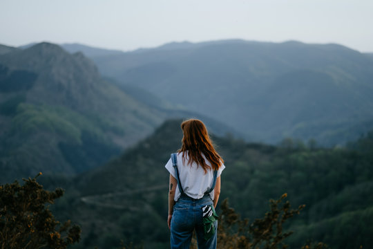 woman backwards looking to a stunning natural mountain landscape of the basque county