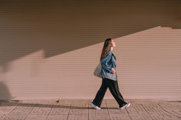Young asian woman walking on street in the sunny day.