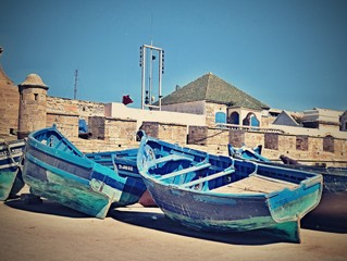 Fototapeta na wymiar Group of blue fishing boats on the shore at the pier in the city of Essaouira Morocco