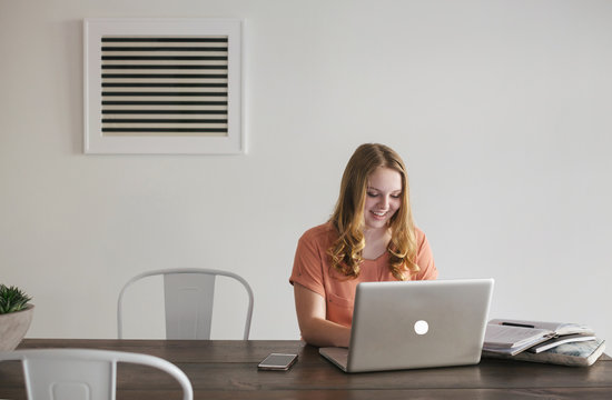 Happy teenage girl working on computer in office