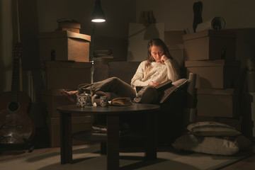 Woman reading a book in messy bedroom